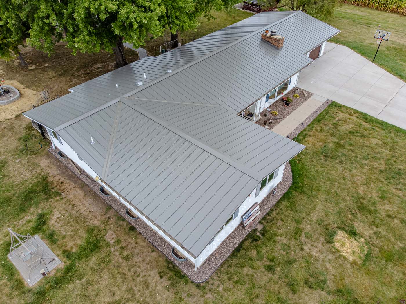 Aerial view of a gray standing-seam metal roof on a single-story house with vertical panel ribs